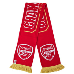 Arsenal FC Gold Premier League Champions Scarf LKT Sport Red and white jacquard knit scarf with gold fringeWith Champions 25/26 text in white and goldBoth sides feature a large Arsenal club crest and Premier League trophy at each endOfficial licensed prod